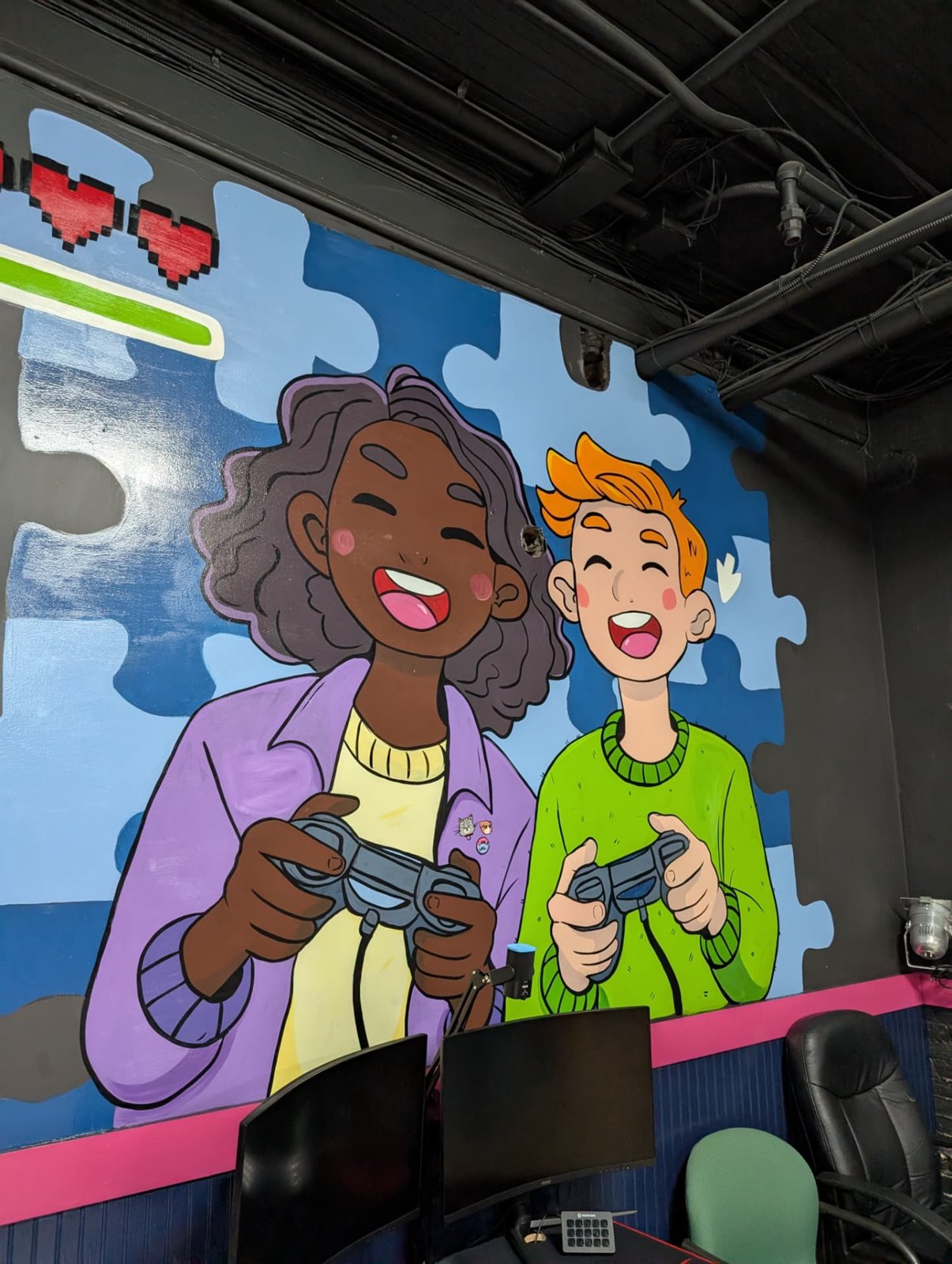 The Connect Center's game room mural of two friends laughing with controllers