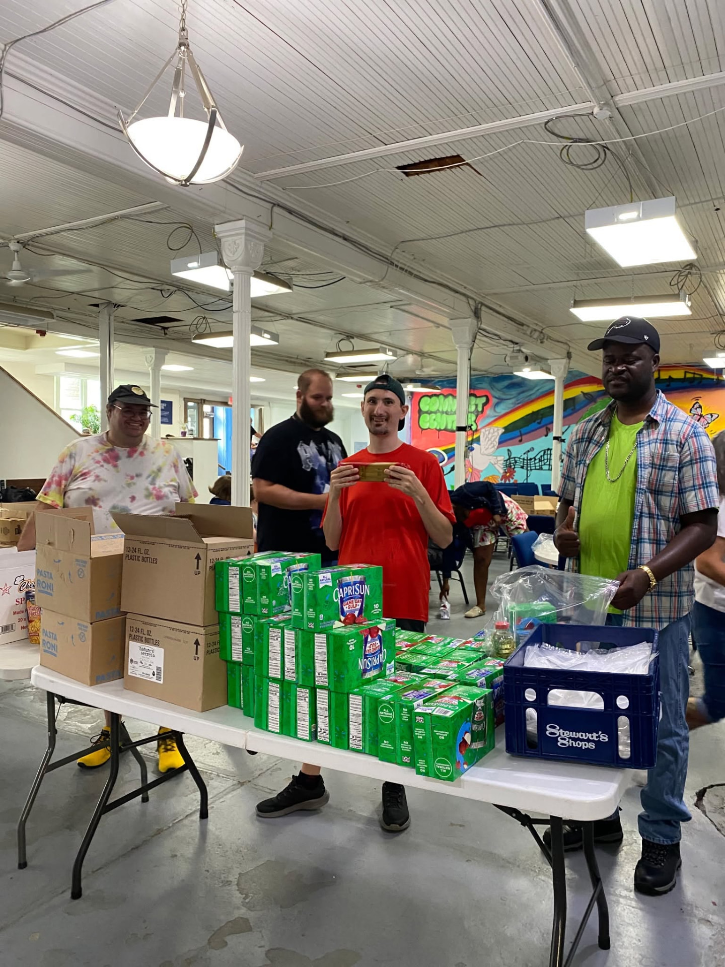 Volunteers stocking a table with juice boxes, pasta and pantry staples at the Connect Center food pantry